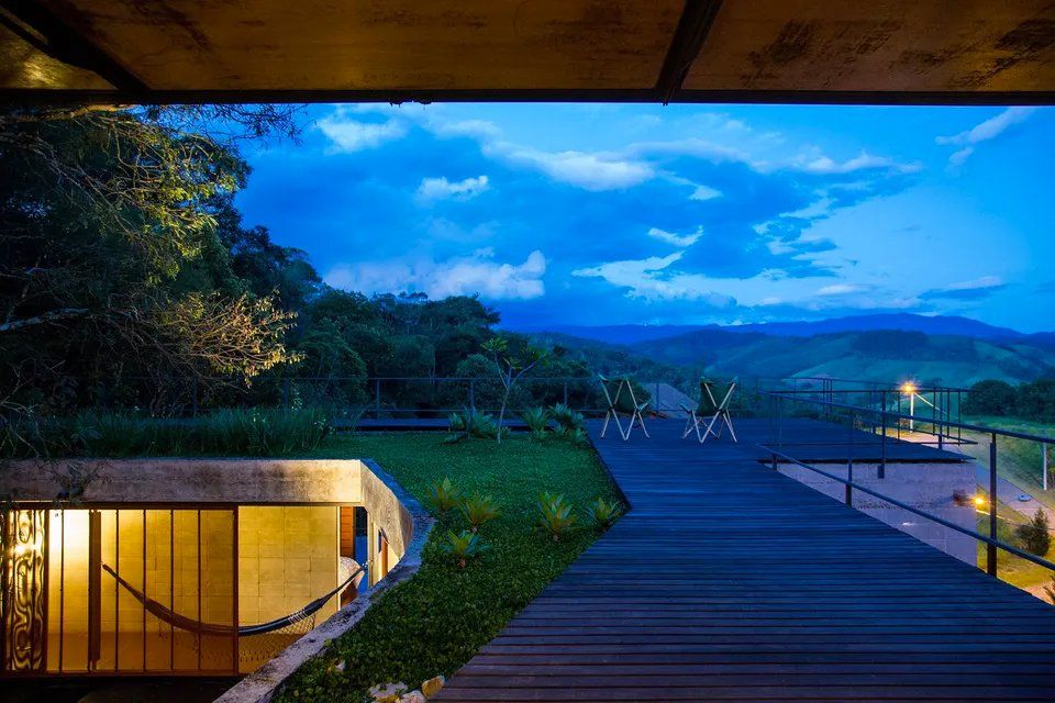 Uma casa com rede no deck e vista para as montanhas à noite.