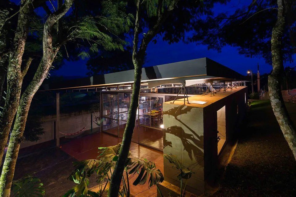 Uma casa é iluminada à noite cercada por árvores.