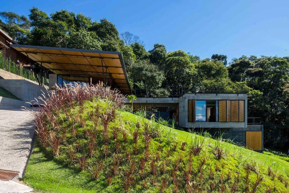 Uma casa está situada no topo de uma colina cercada por árvores.