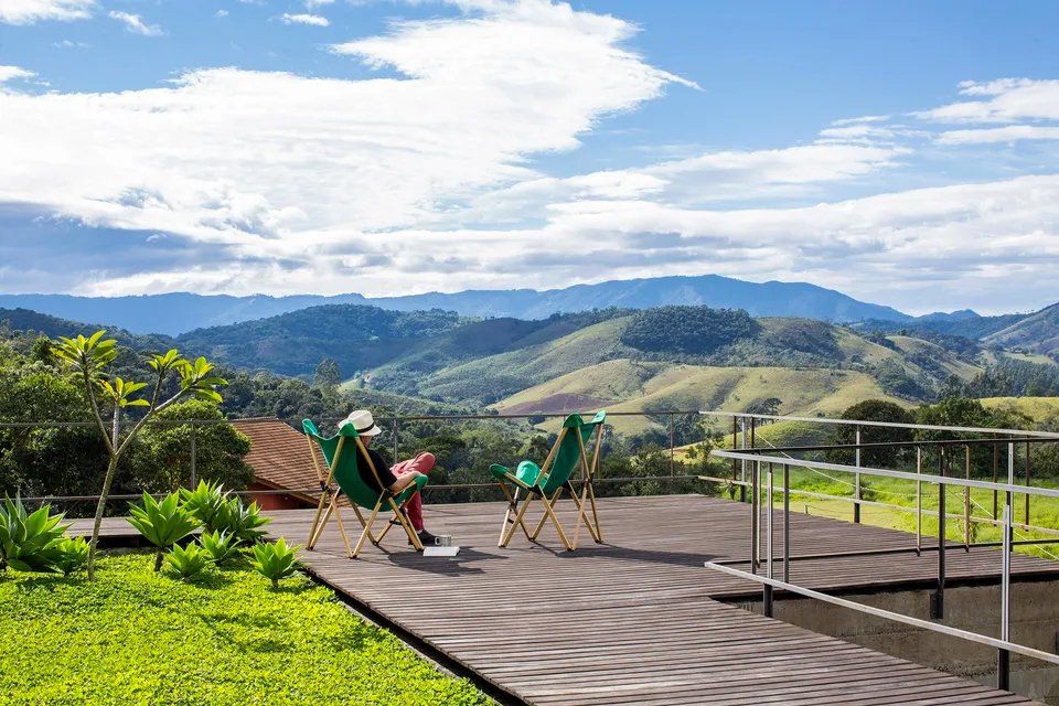 Algumas cadeiras estão sentadas em um deck de madeira com vista para uma cordilheira.