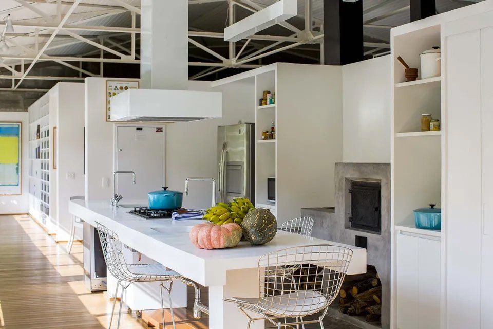 Uma cozinha com uma grande ilha no meio e uma lareira.