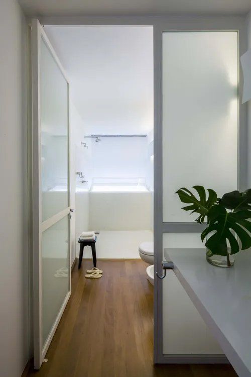 Uma casa de banho com porta de vidro que dá acesso a uma banheira.