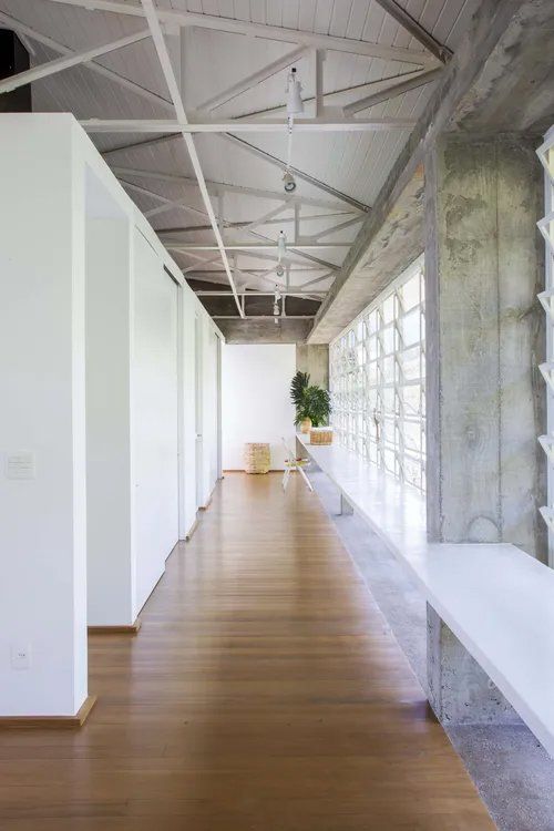 Um longo corredor com piso de madeira e paredes brancas