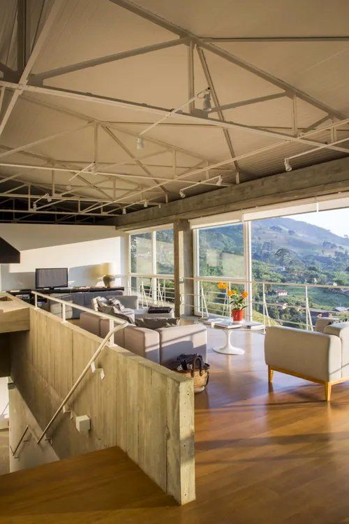 Uma sala de estar com muitas janelas e escadas que levam até ela.