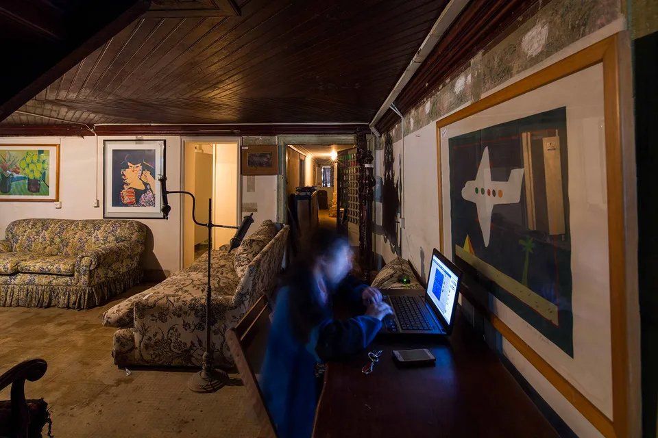 Uma pessoa está sentada em uma mesa com um laptop em uma sala de estar.