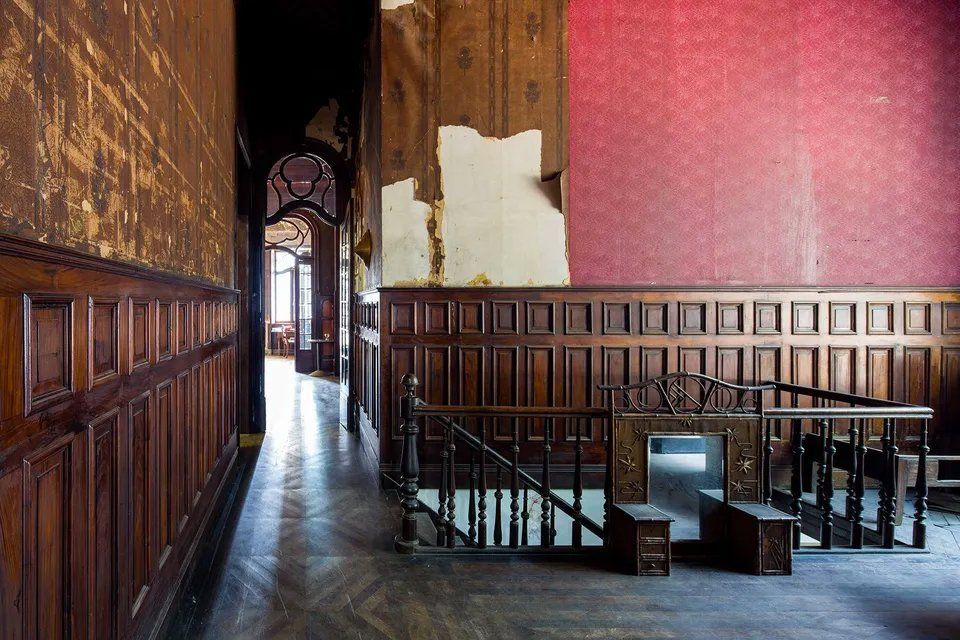 Um corredor com painéis de madeira e uma escada em um prédio antigo.