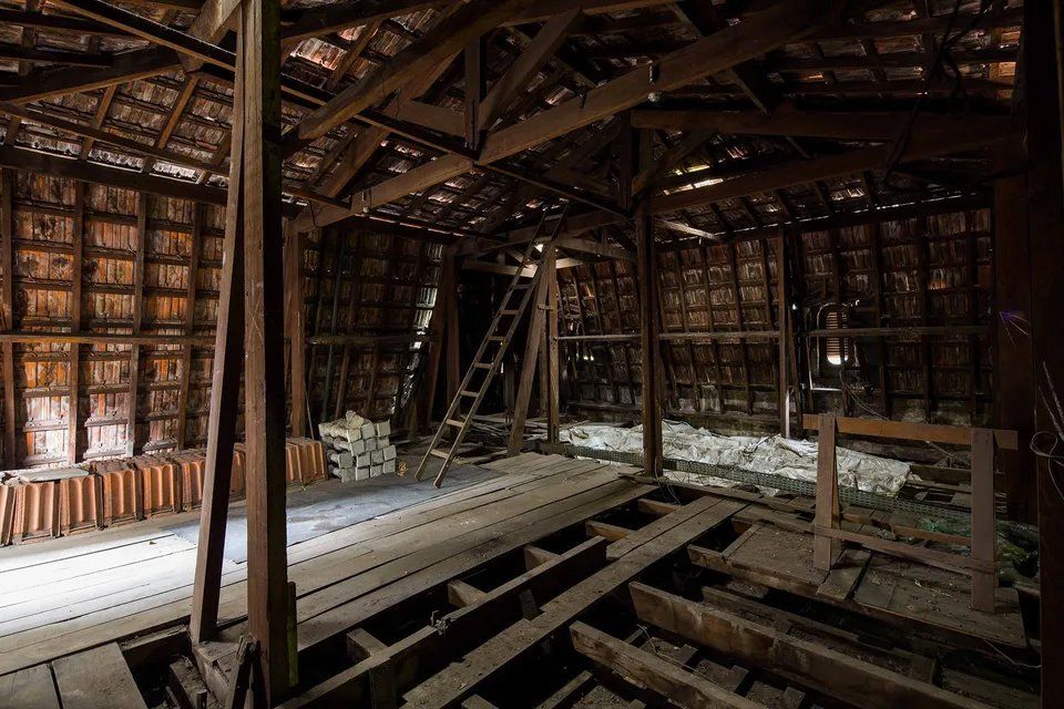 Há uma escada no sótão de um prédio antigo.