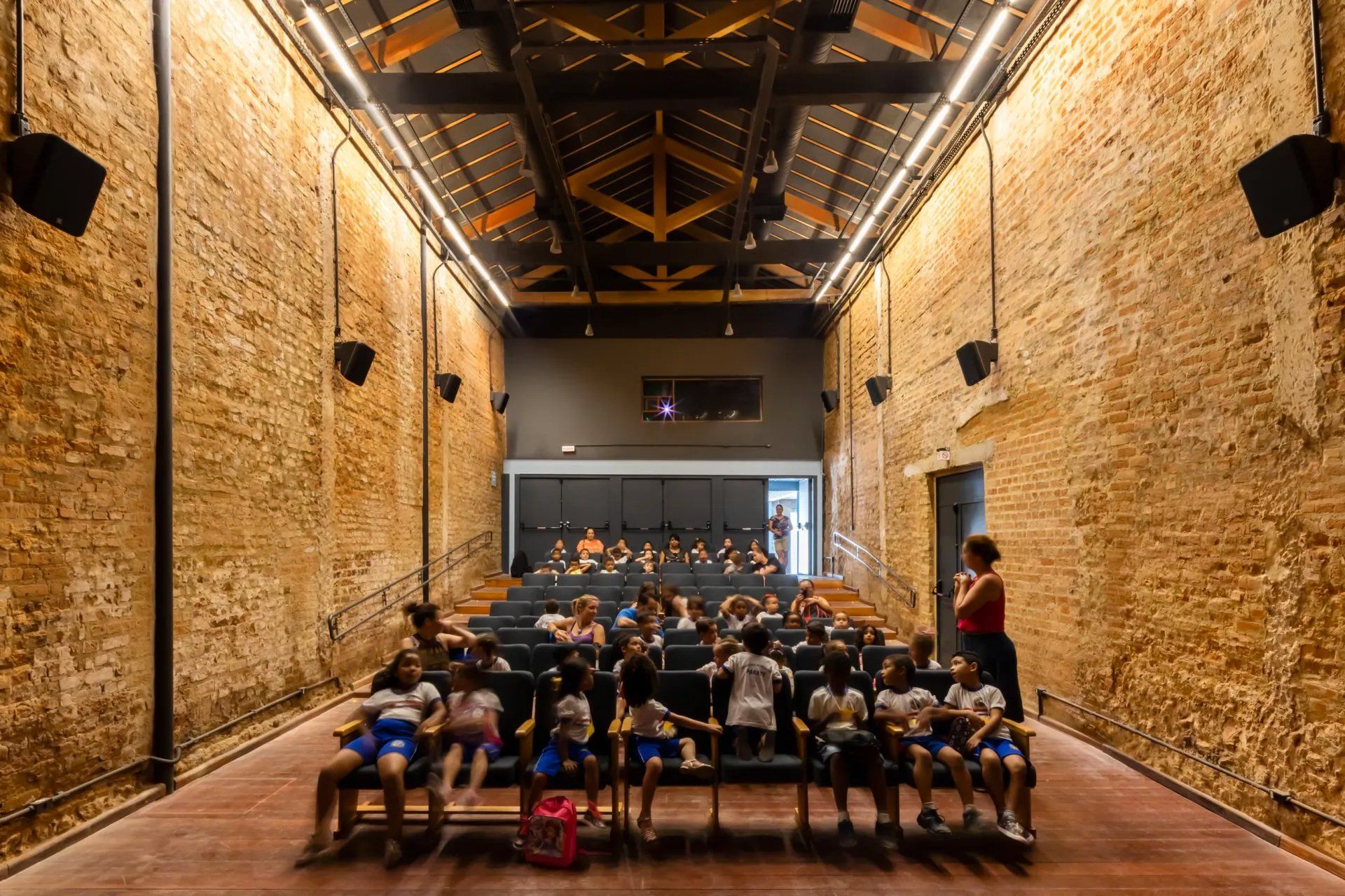 Um grupo de crianças está sentado em um grande auditório.