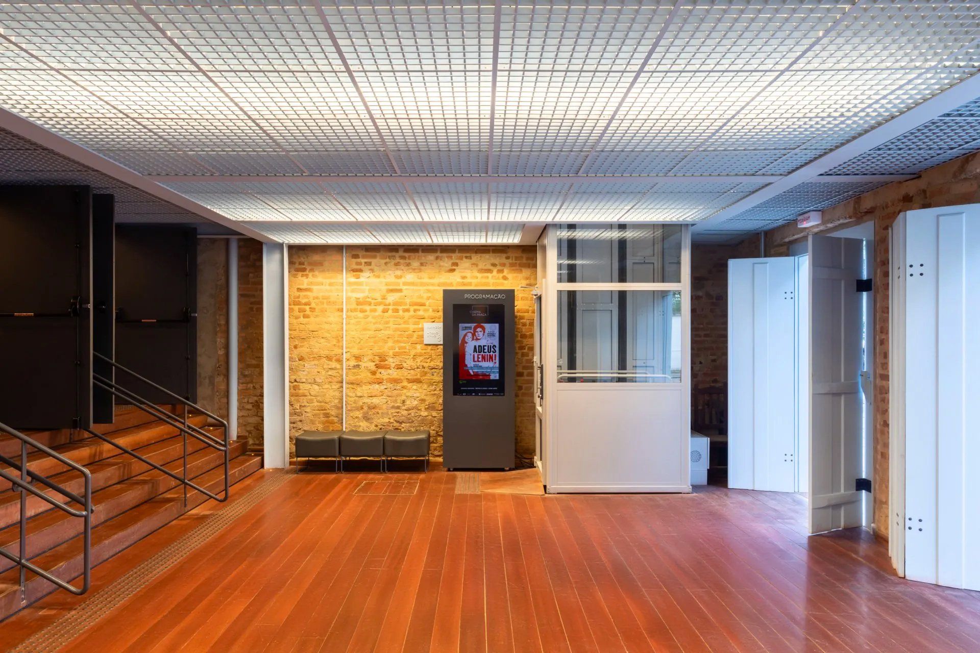 Uma grande sala vazia com piso de madeira e escadas.