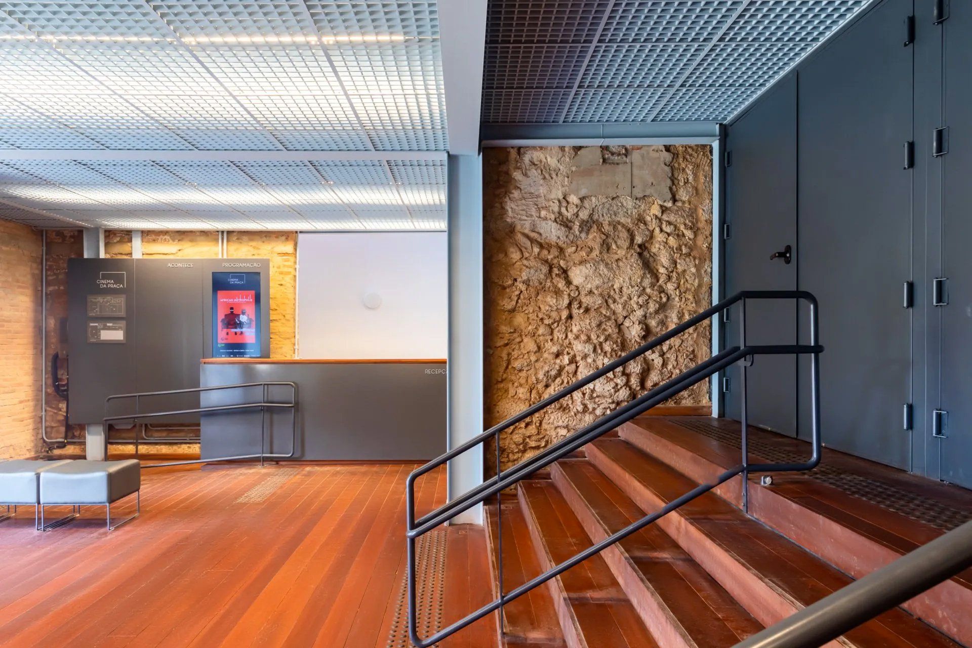 Uma escada em um prédio com piso de madeira e corrimão de metal.