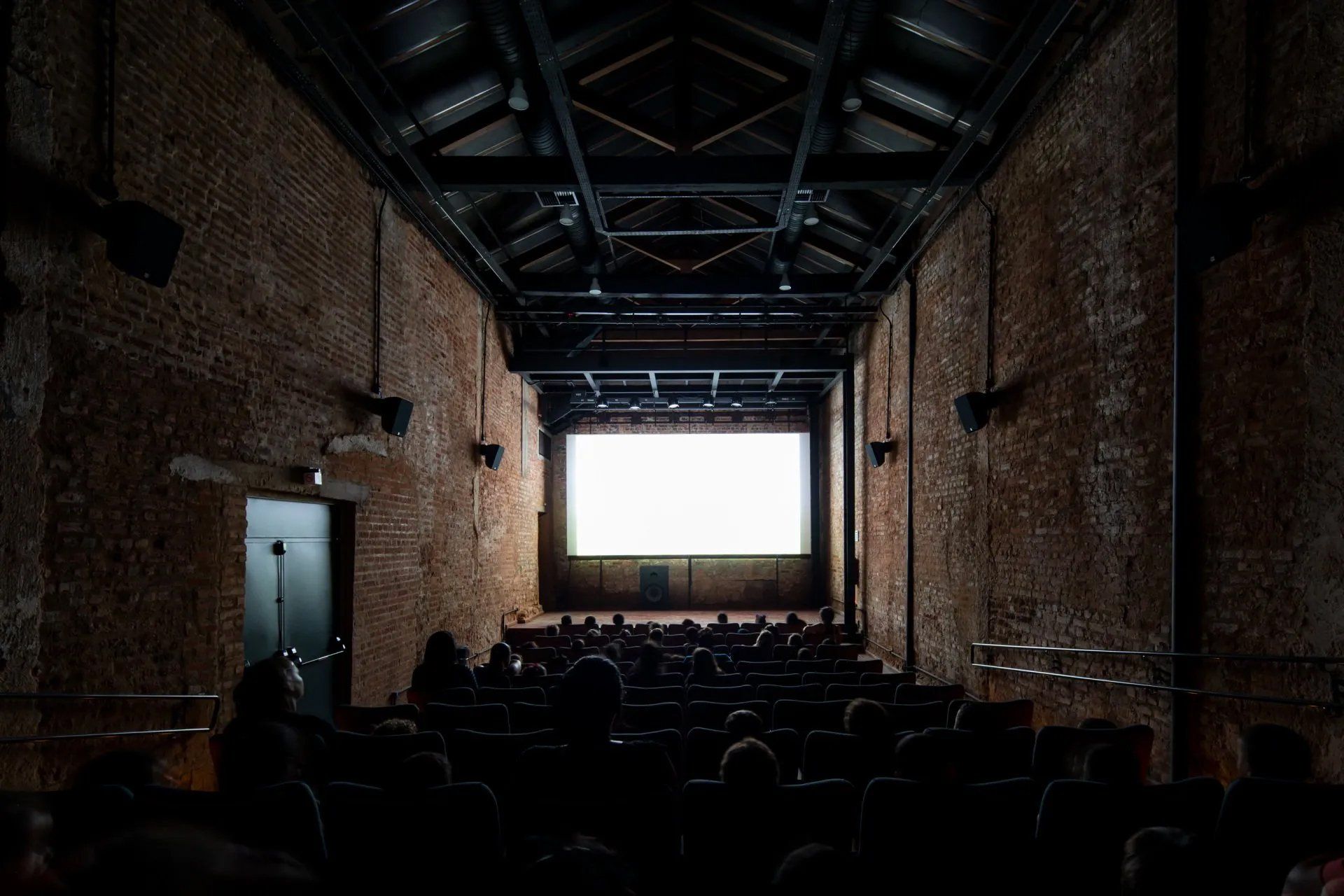 Um grupo de pessoas está sentado em um auditório escuro assistindo a um filme.