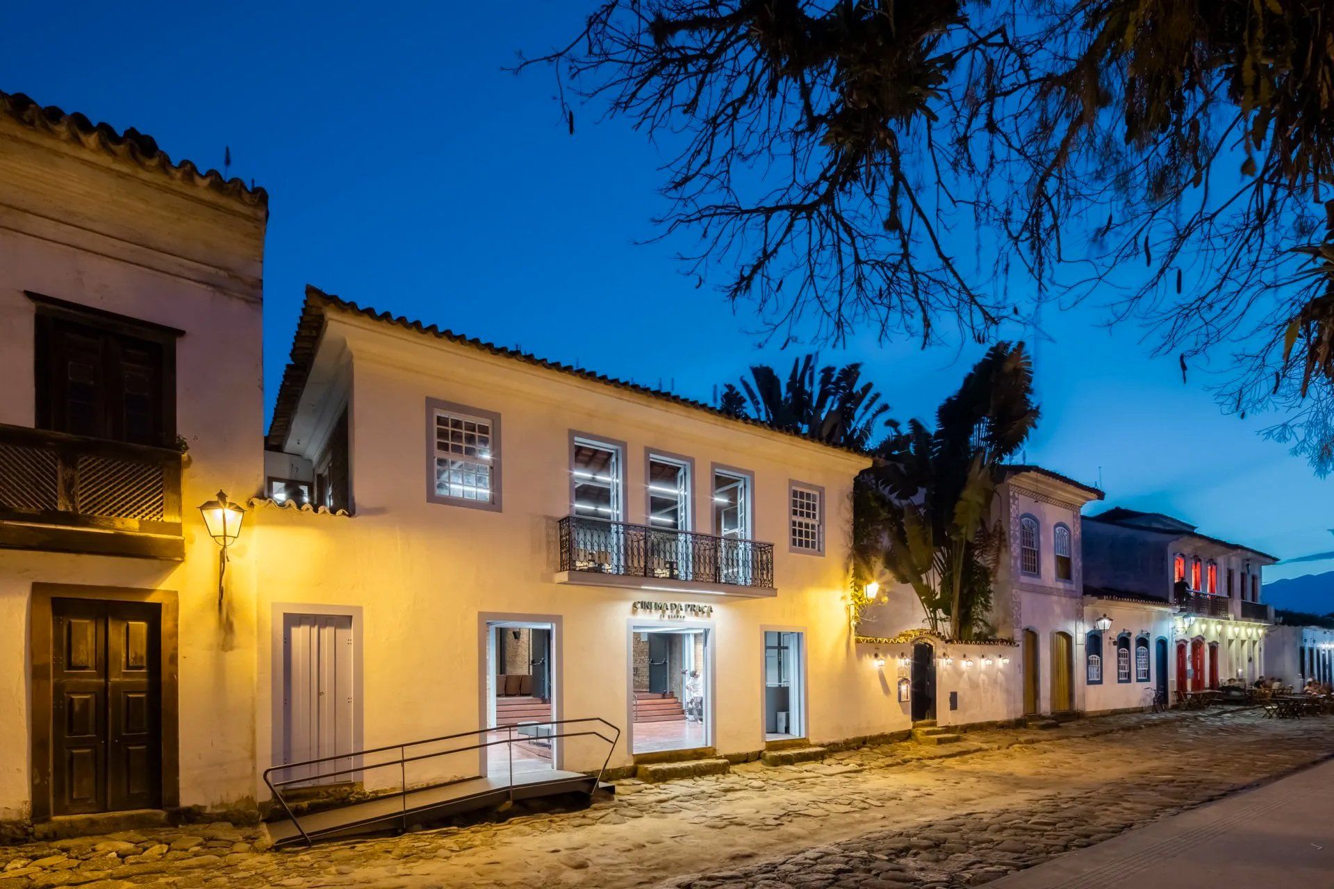 Um prédio branco com varanda fica iluminado à noite.