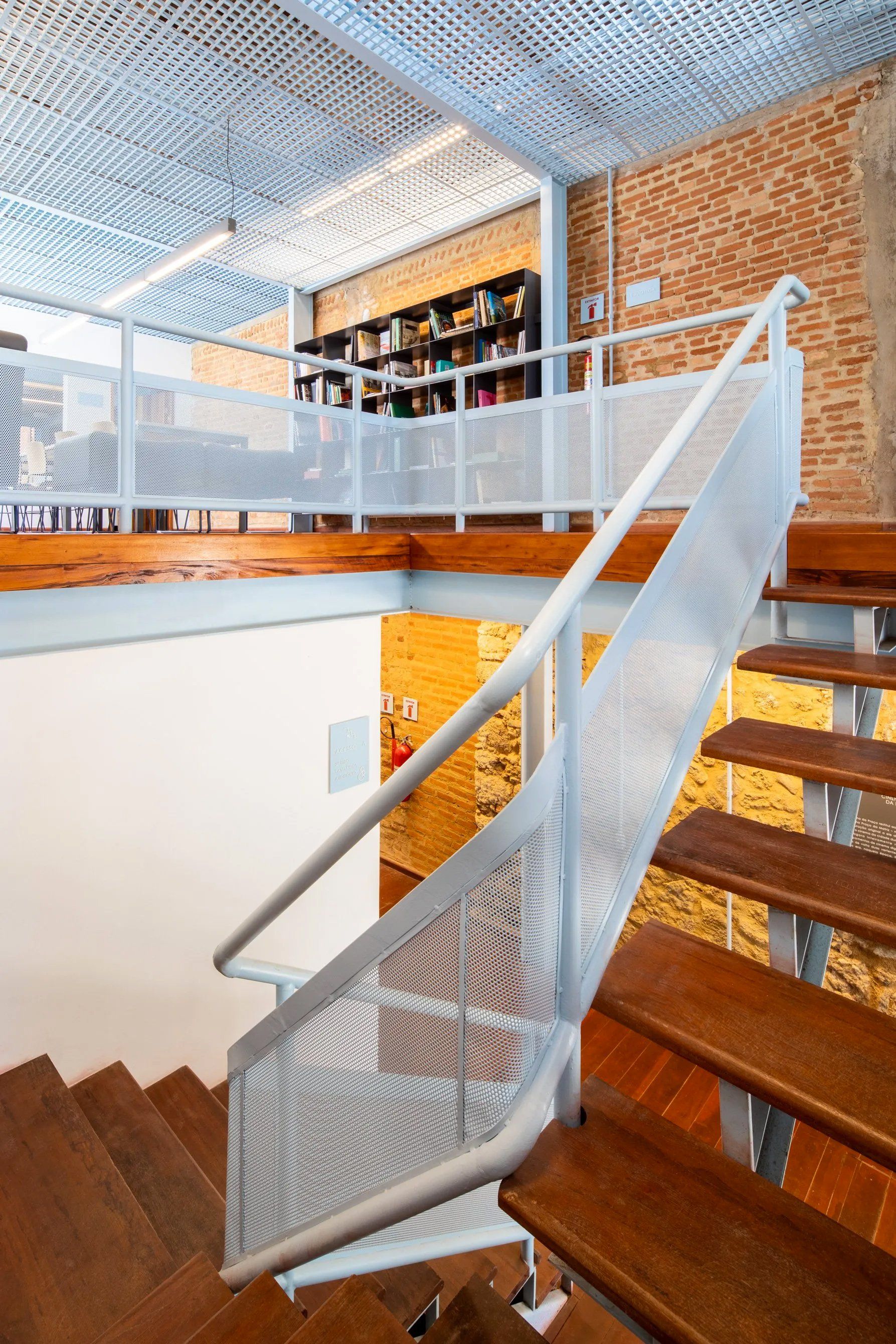 Uma escada de madeira com corrimão de metal que leva ao segundo andar.