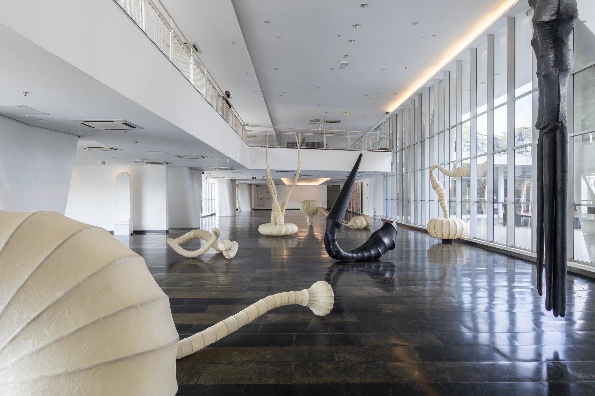 Uma grande sala com muitas janelas e esculturas no chão.