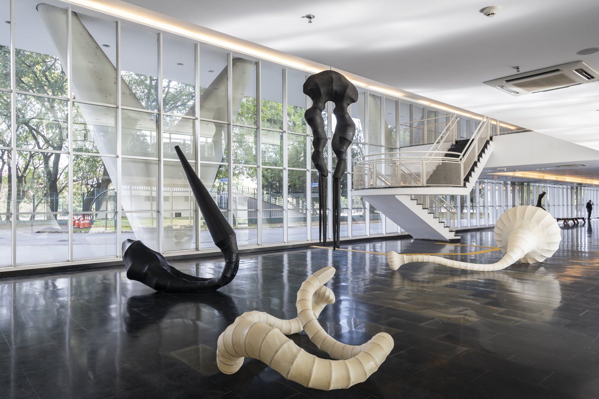 Uma grande sala com muitas janelas e esculturas no chão.