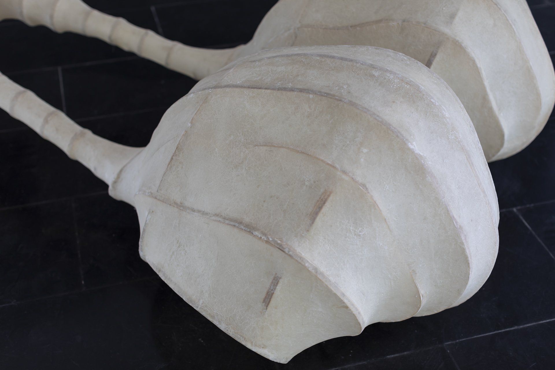 Duas esculturas brancas estão sentadas sobre uma superfície preta