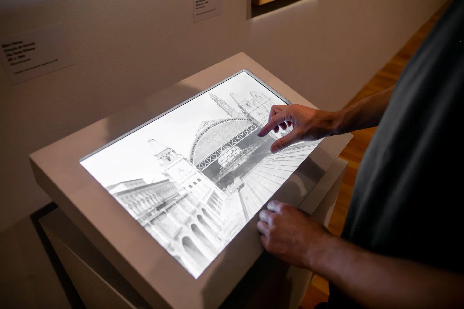 Uma pessoa está apontando para uma tela com a imagem de um edifício