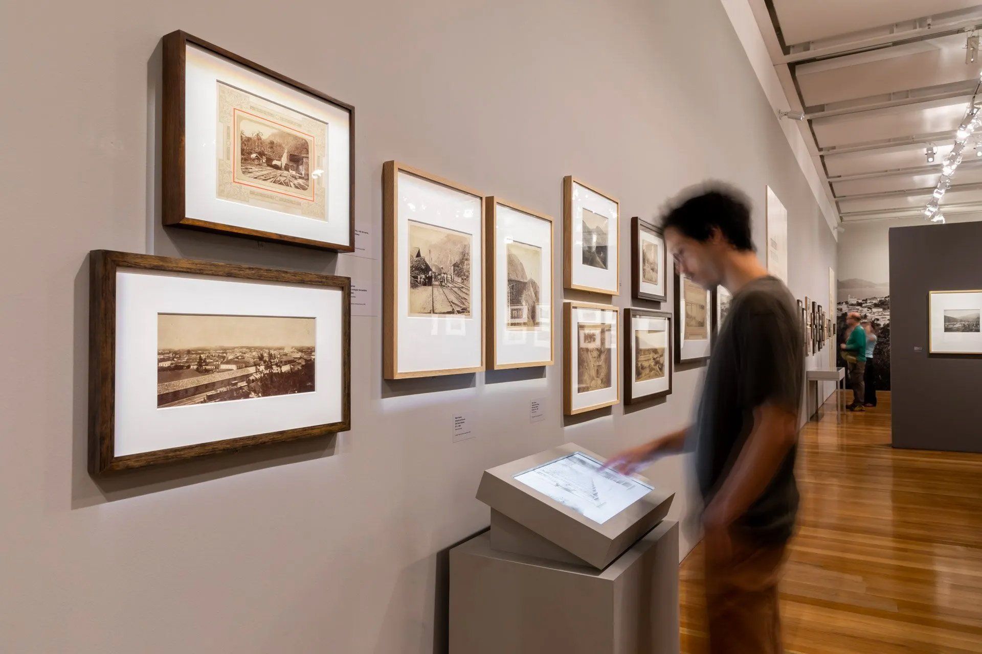 Um homem está olhando para uma exposição de pinturas em um museu.