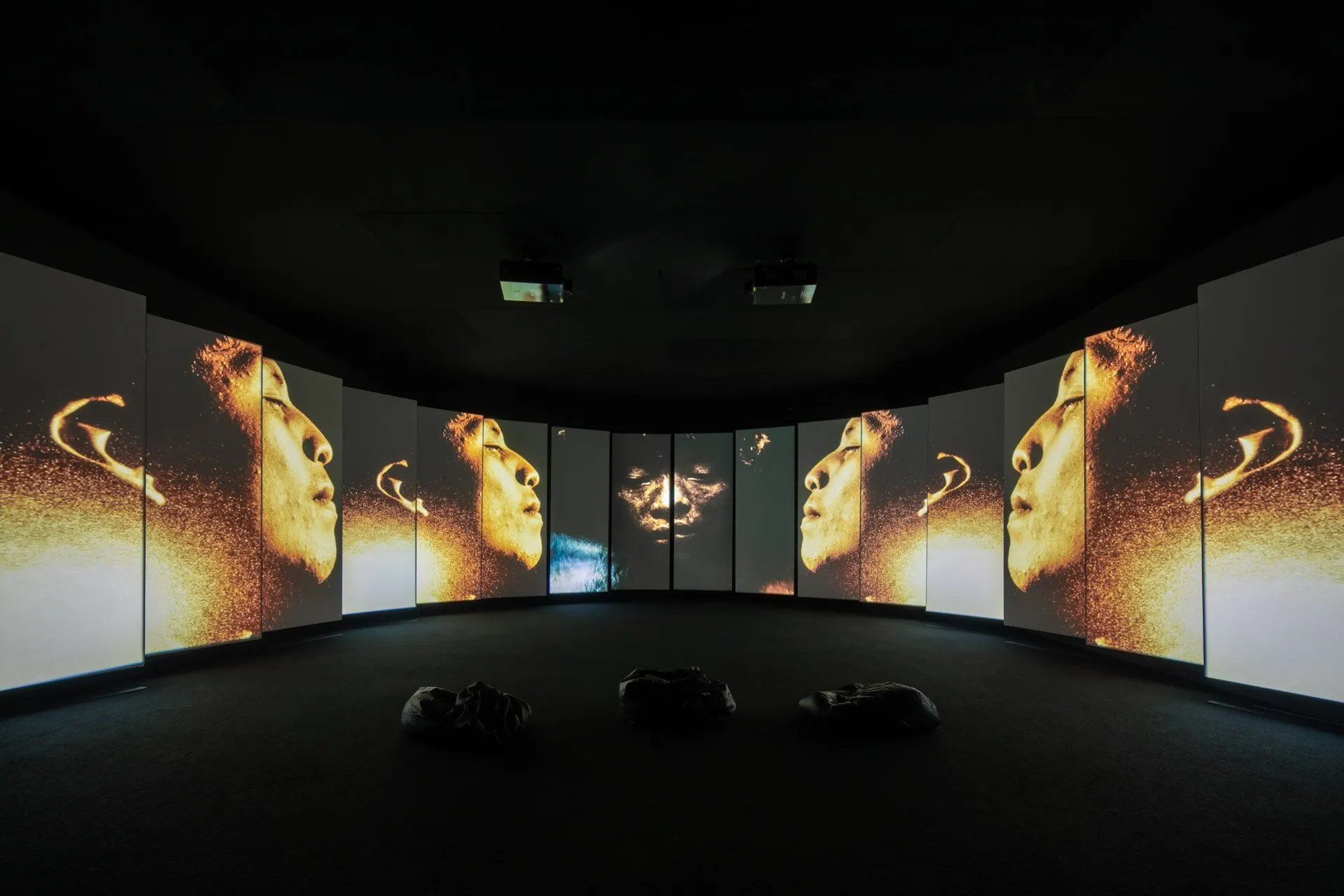 Uma sala com muitas telas exibindo imagens do rosto de uma mulher.