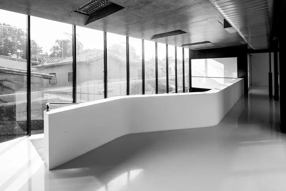 Uma foto em preto e branco de um corredor vazio com uma grande janela.