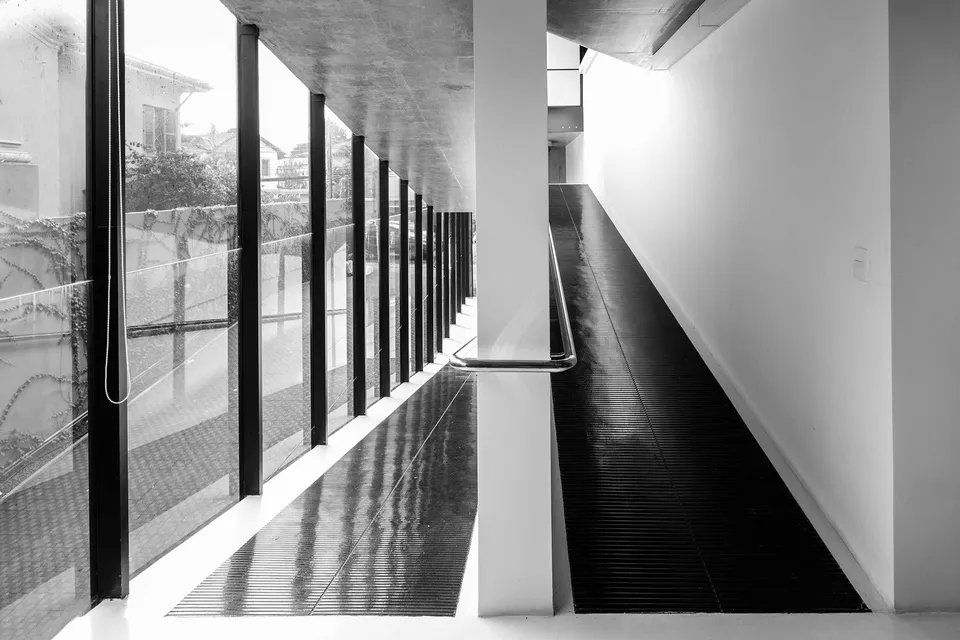 Uma foto em preto e branco de um longo corredor com muitas janelas