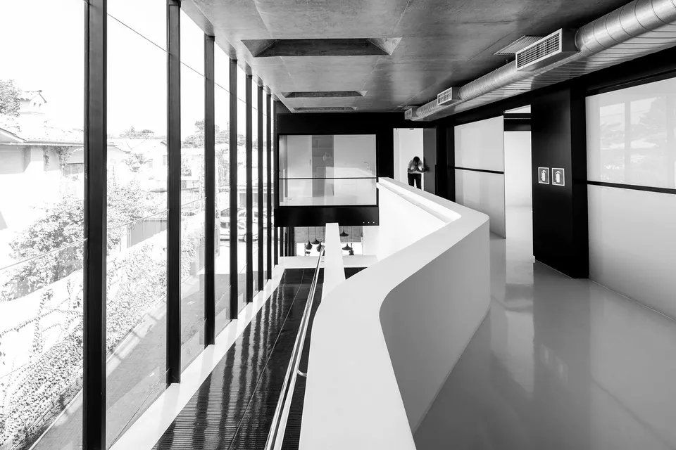 Uma foto em preto e branco de um corredor de um prédio com muitas janelas.