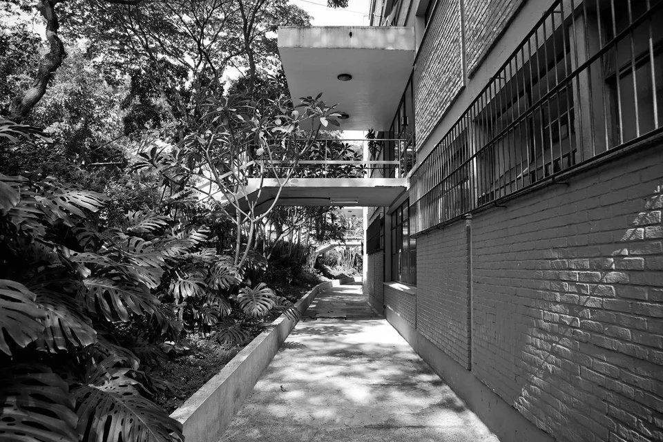 Uma foto em preto e branco de uma passarela entre dois edifícios