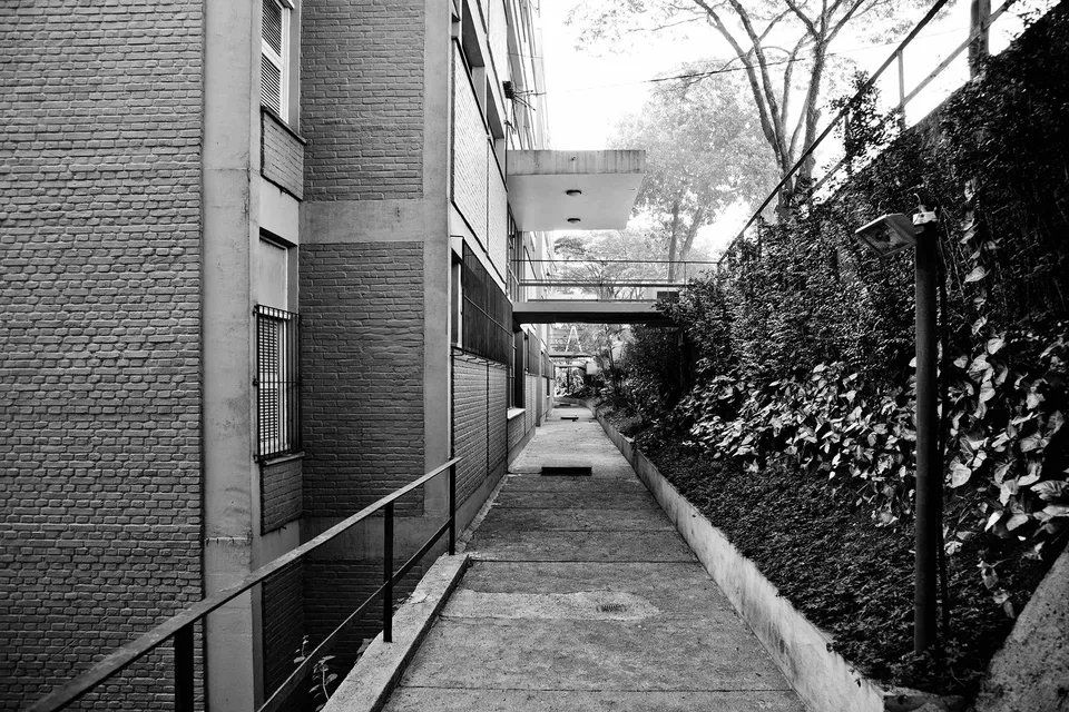 Uma foto em preto e branco de uma passarela entre dois edifícios.