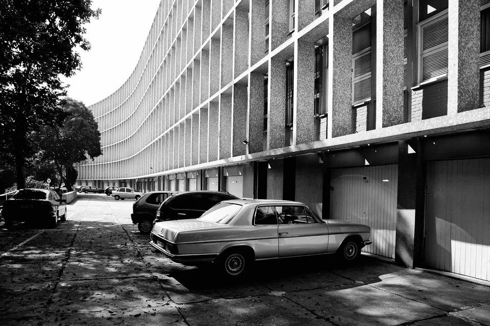 Uma foto em preto e branco de um carro estacionado em frente a um prédio.