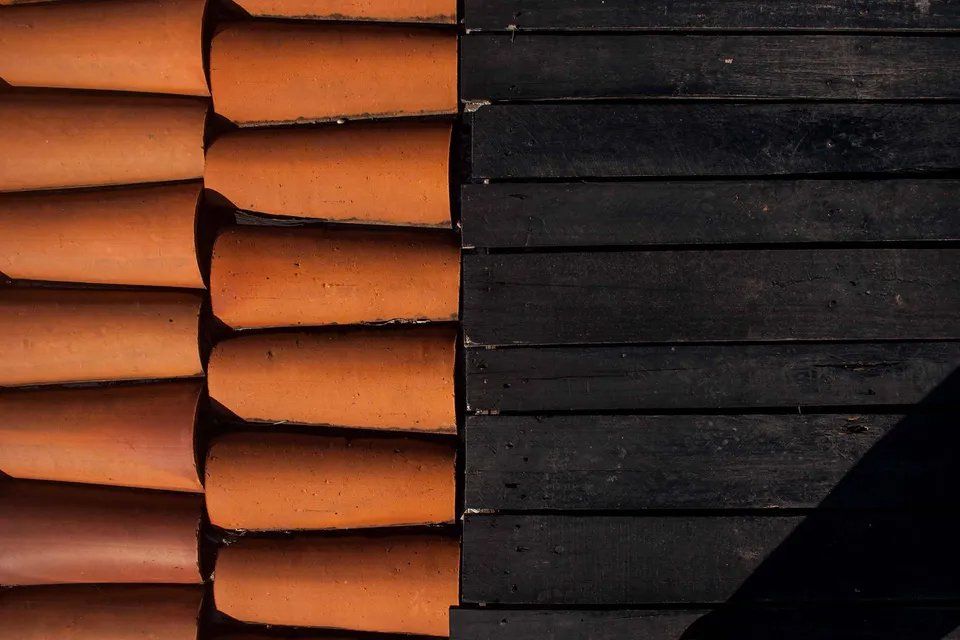 Uma fileira de telhas de barro ao lado de uma superfície de madeira preta