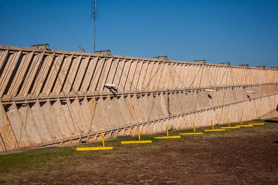 Um grande muro de concreto com postes amarelos na frente.