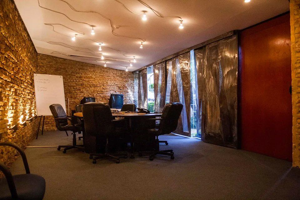 Uma sala de conferências com mesa redonda e cadeiras e parede de tijolos.