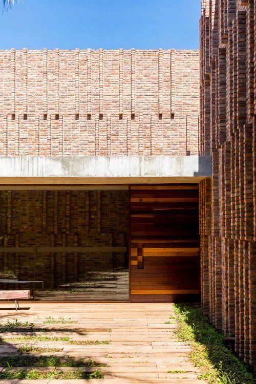 Um prédio de tijolos com uma porta de madeira e uma passarela que leva até ela.