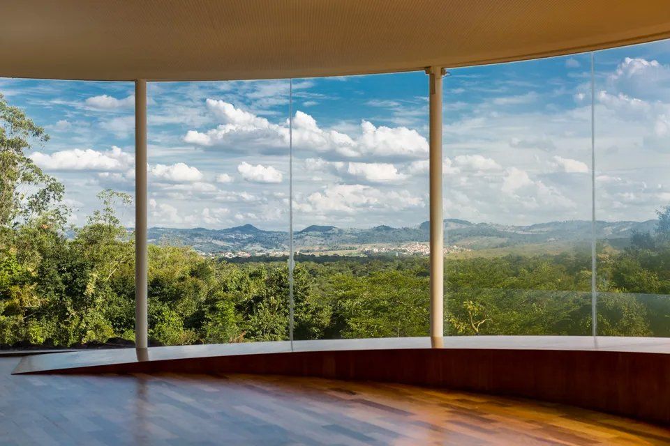 Um quarto vazio com vista para uma floresta pelas janelas.