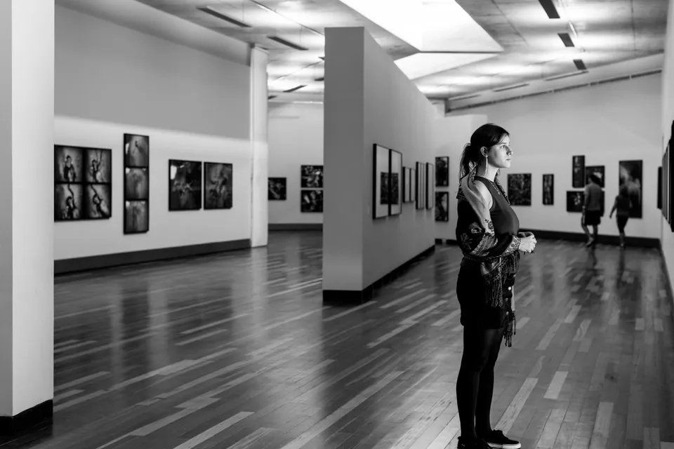 Uma mulher está em um museu olhando pinturas.