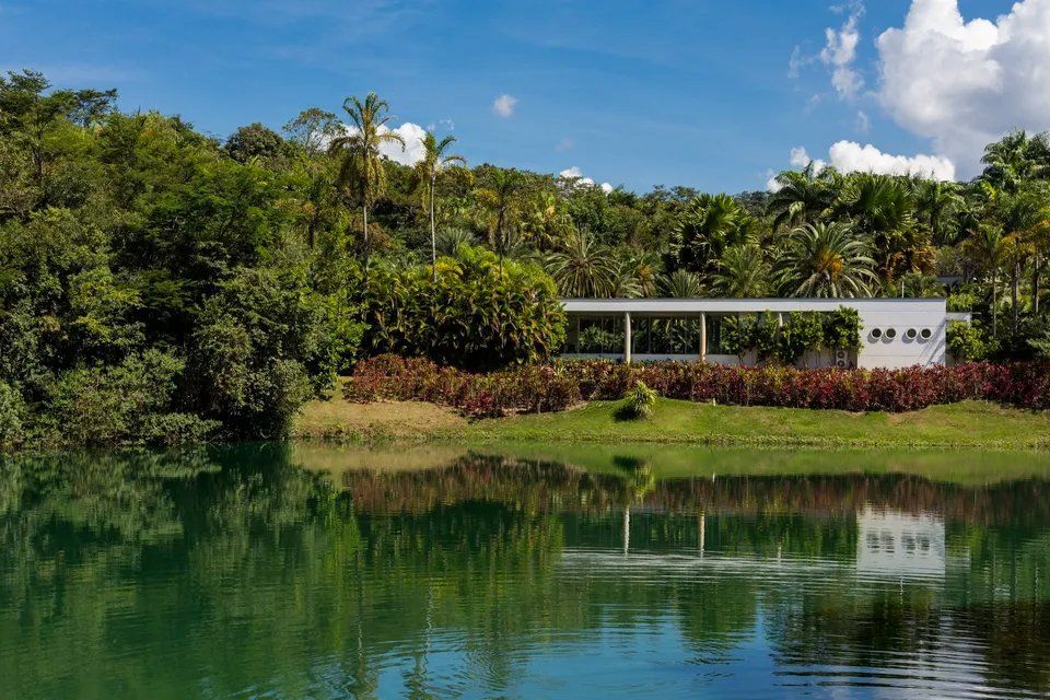 Uma casa está situada às margens de um lago cercada por árvores.