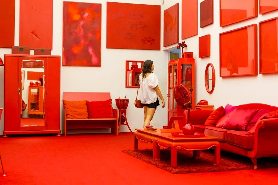 Uma mulher está em uma sala cheia de móveis vermelhos.