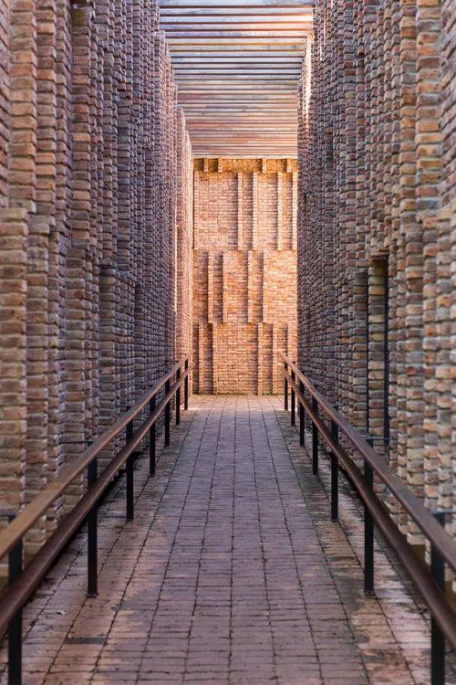 Uma longa passarela de tijolos com uma grade que leva a um prédio.