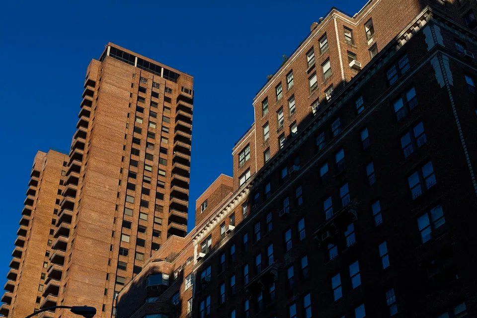 Olhando para dois prédios altos de tijolos contra um céu azul
