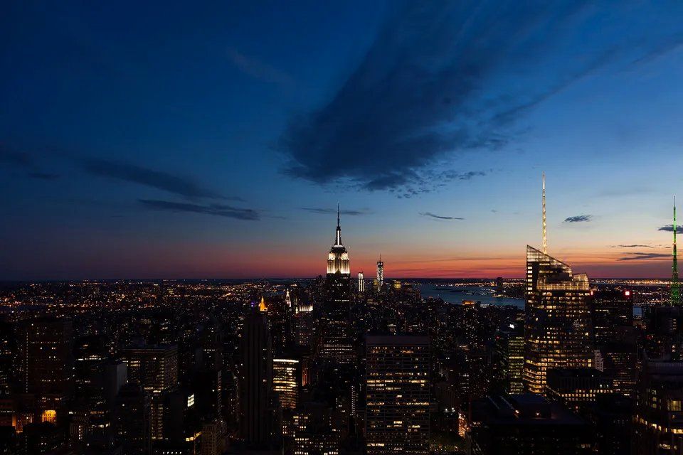 Uma vista aérea de uma cidade à noite com o Empire State Building em primeiro plano