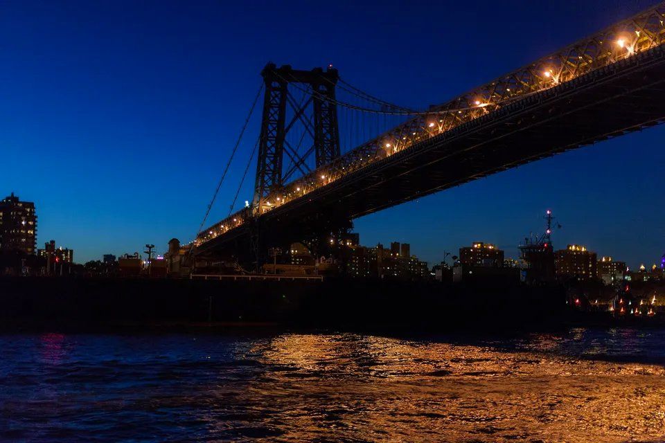 Uma ponte sobre um corpo de água à noite com uma cidade ao fundo.