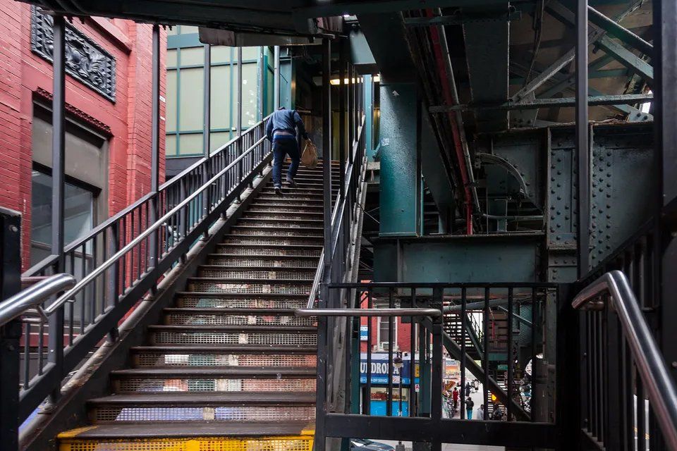 Um homem está subindo uma escada em uma cidade.