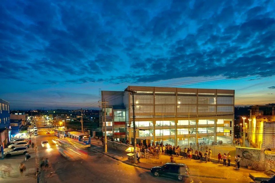 Uma vista aérea de uma cidade à noite com um grande edifício ao fundo.