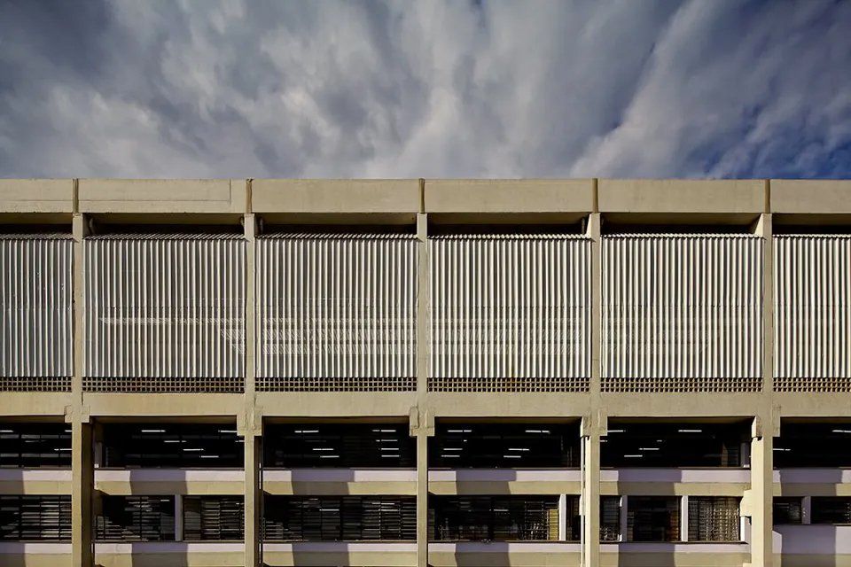 Um grande edifício com muitas janelas e um céu nublado ao fundo.