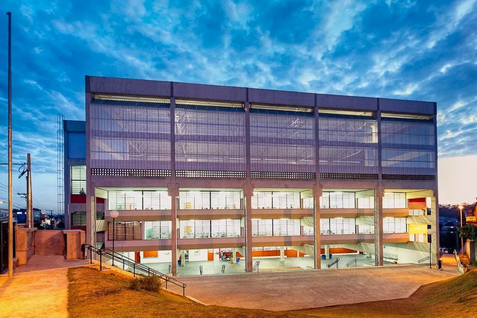 Um grande edifício com muitas janelas fica iluminado à noite.