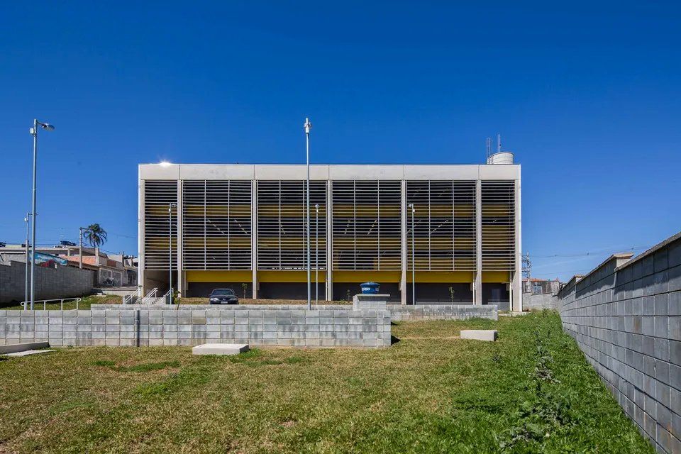 Um grande edifício com muitas janelas está situado no meio de um campo gramado.