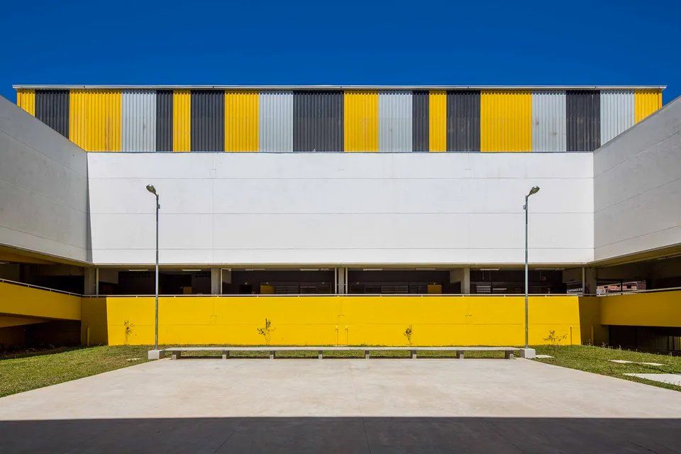 Um grande edifício branco e amarelo com um estacionamento em frente.