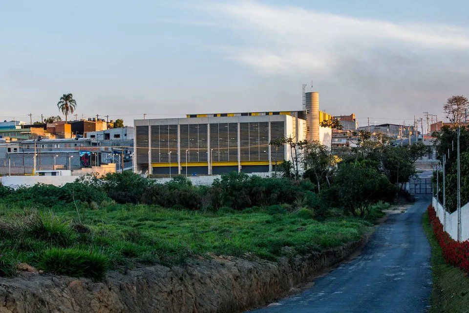 Uma estrada de terra que leva a um grande edifício no meio de um campo.