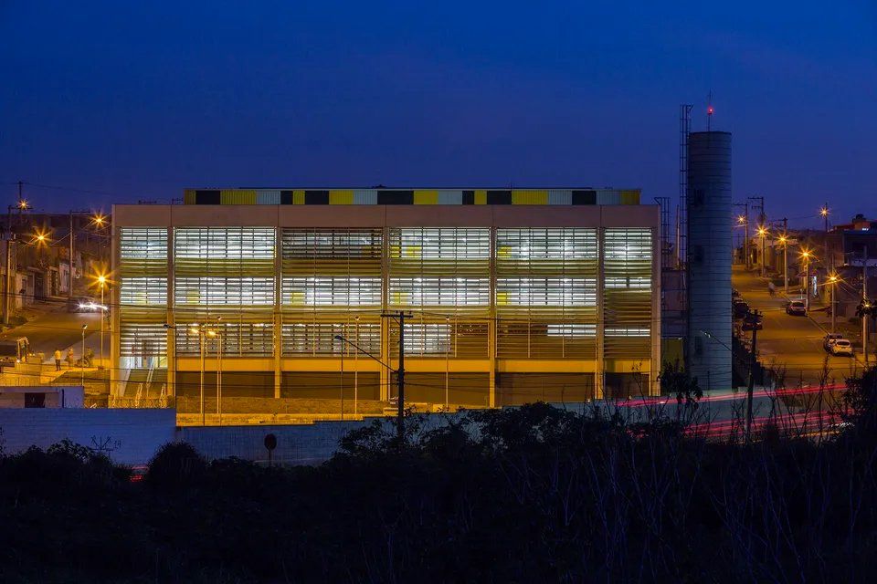 Um grande edifício com muitas janelas fica iluminado à noite.
