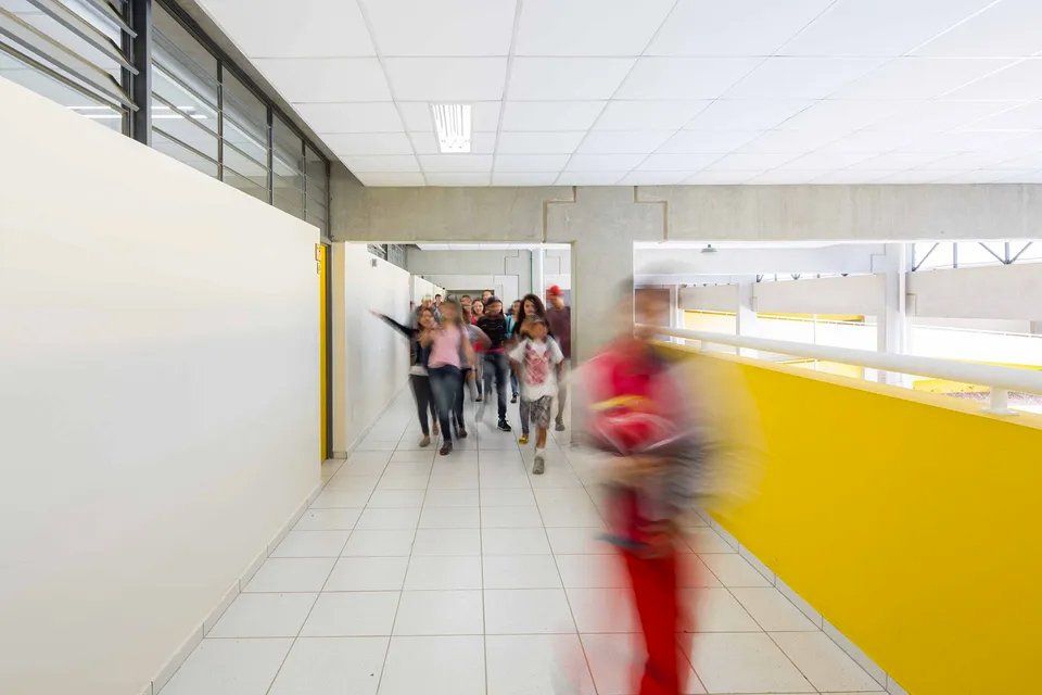 Um grupo de pessoas está andando pelo corredor de uma escola.